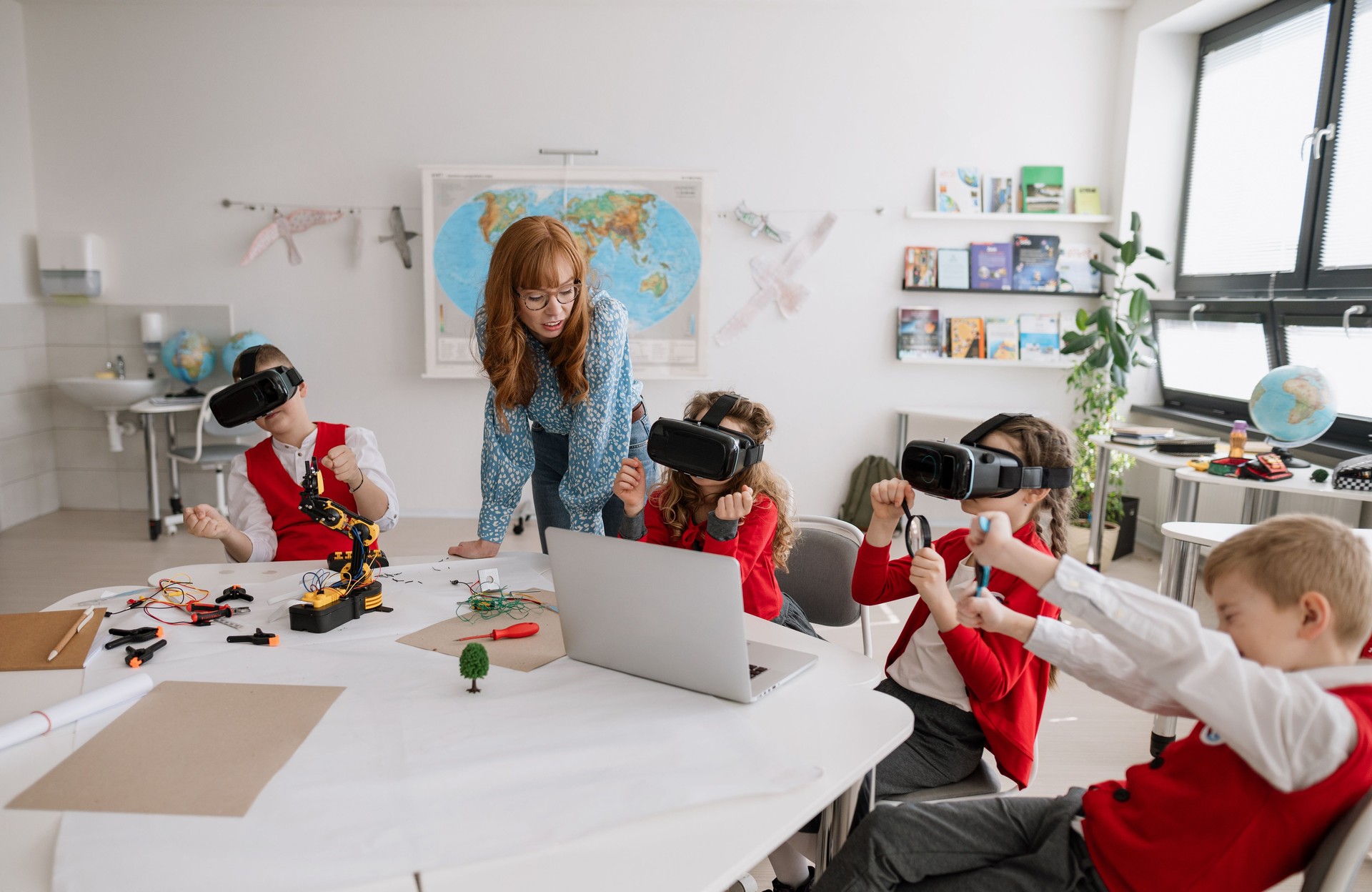 Happy schoolchildren wearing virtual reality goggles at school in computer science class